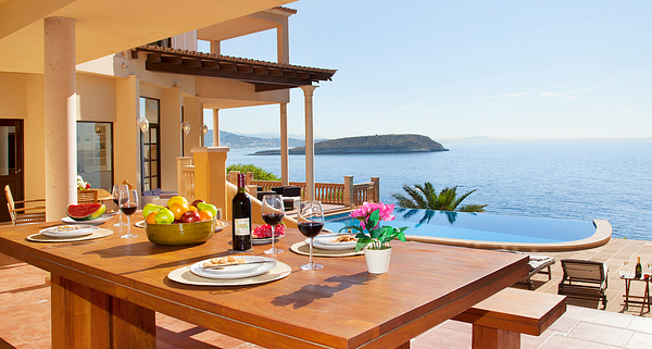 A luxurious Mediterranean-style villa featuring an elegant outdoor pool area with lush greenery and classic architecture.