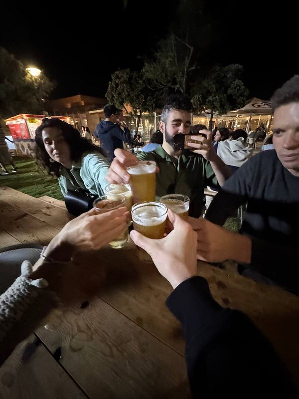 A group of friends is toasting with beers at a festival during the night.