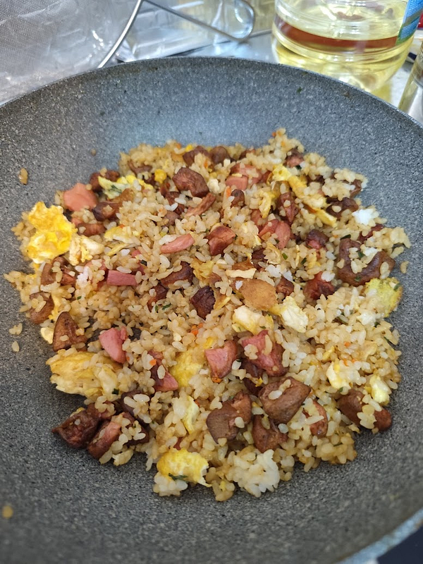 A pan filled with freshly cooked nasi goreng, featuring rice, meat, and egg.