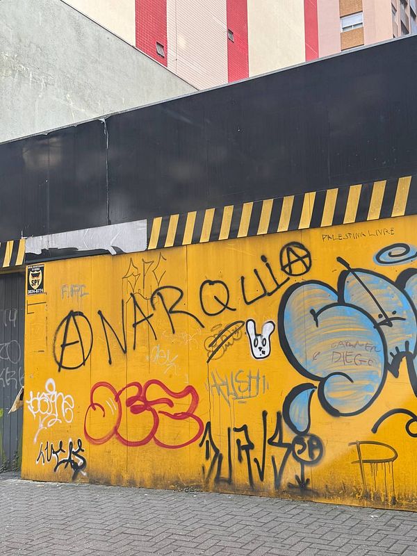 A vibrant urban wall covered in graffiti, featuring various tags and symbols.
