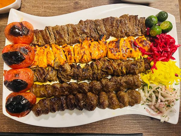 A vibrant mixed grill platter featuring various types of grilled meats and colorful accompaniments.