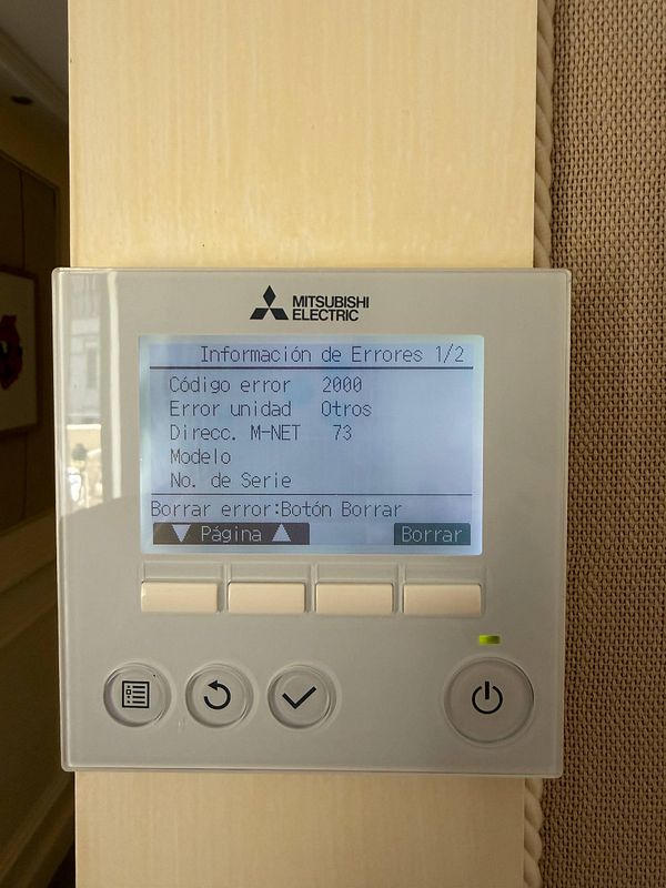 Photograph of a hotel room thermostat panel displaying an error message in Catalan with icons for temperature, fan, and settings controls.