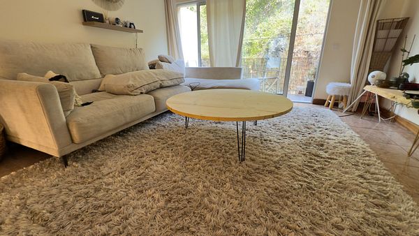 A cozy living room featuring a homemade round table on a plush rug.