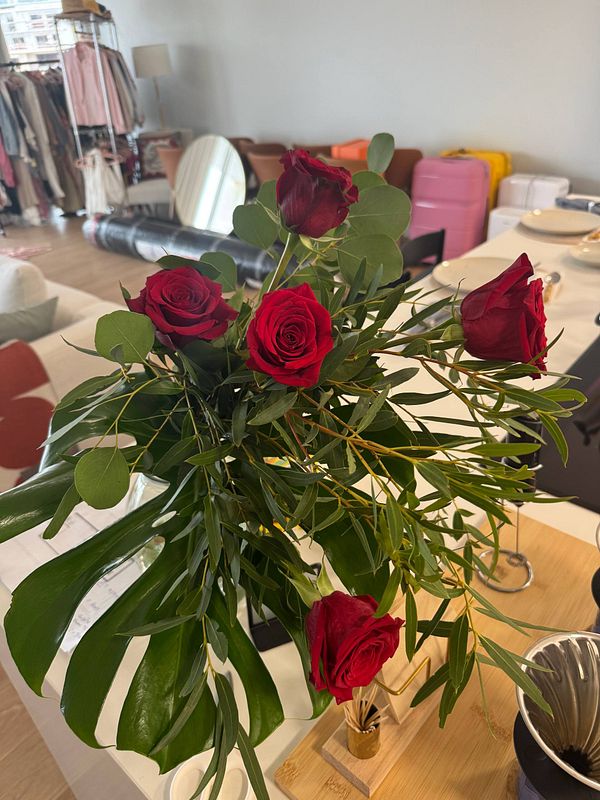 A bouquet of red roses is prominently displayed on a table in a modern interior setting.