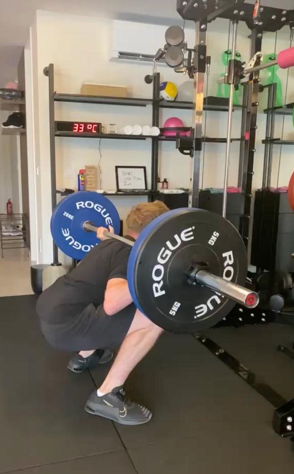 A man in workout attire performing a dumbbell bench press exercise at home.
