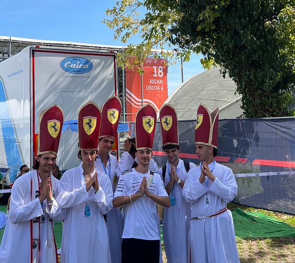 A group of fans dressed in elaborate costumes poses for a photo at a motorsport event.
