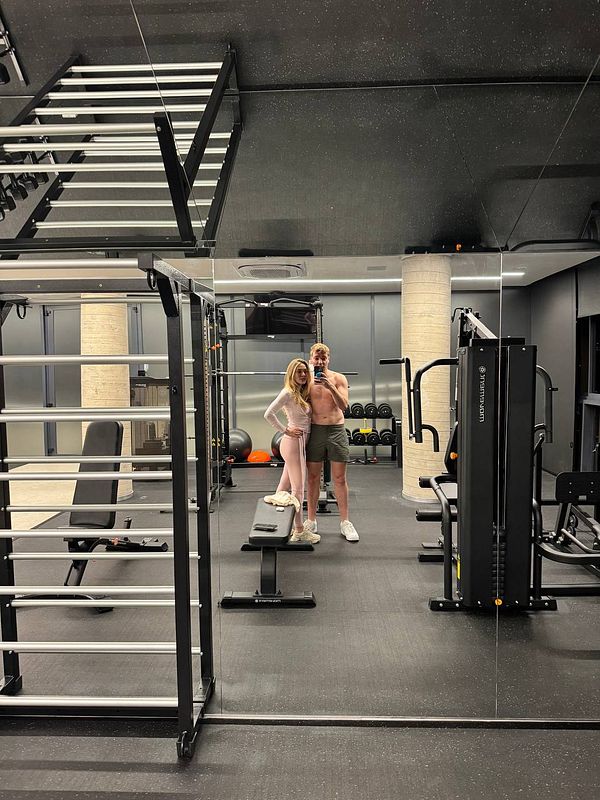 A couple poses together in a modern gym setting.