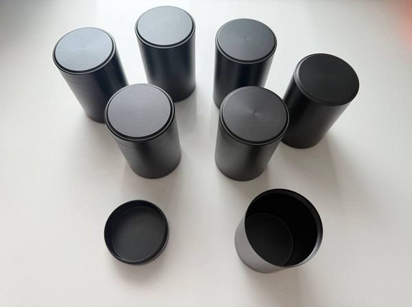 A set of four stainless steel metal jars with lids on a wooden surface.