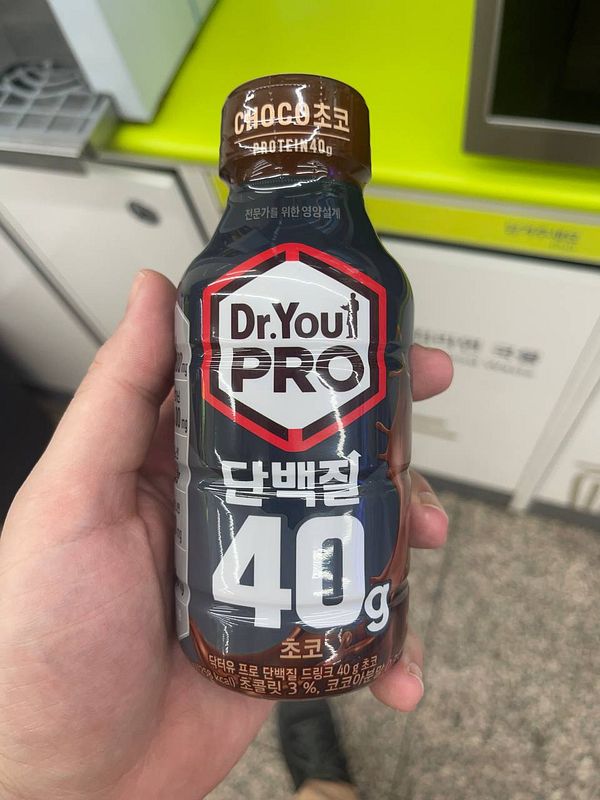 A hand holds a bottle of Dr. You PRO protein drink.