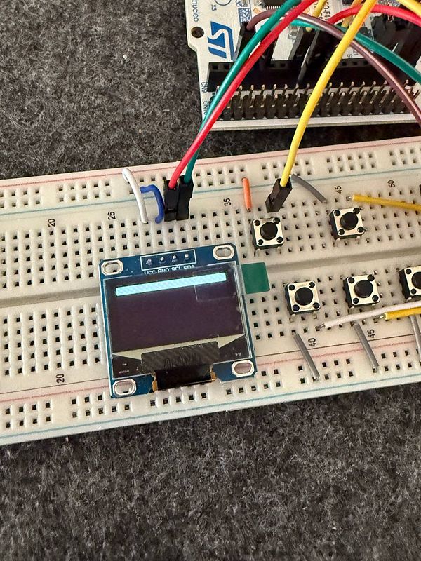 A test setup featuring an STM32 microcontroller connected to a small display and buttons on a breadboard.