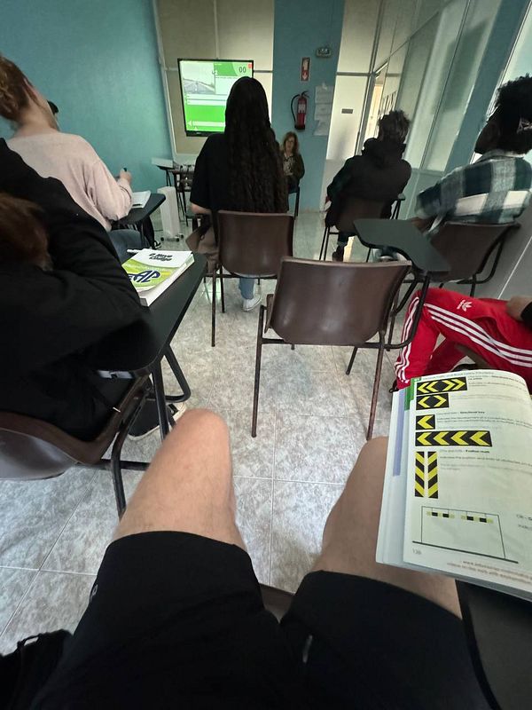 A classroom setting during a driving class with students seated and a presentation on a screen.