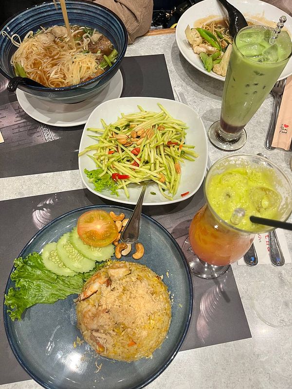 A vibrant spread of Thai dishes is presented on a dining table.