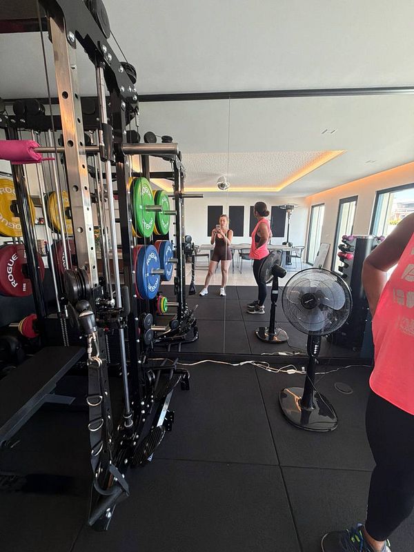 A woman in workout attire is lifting a heavy barbell in a gym setting.