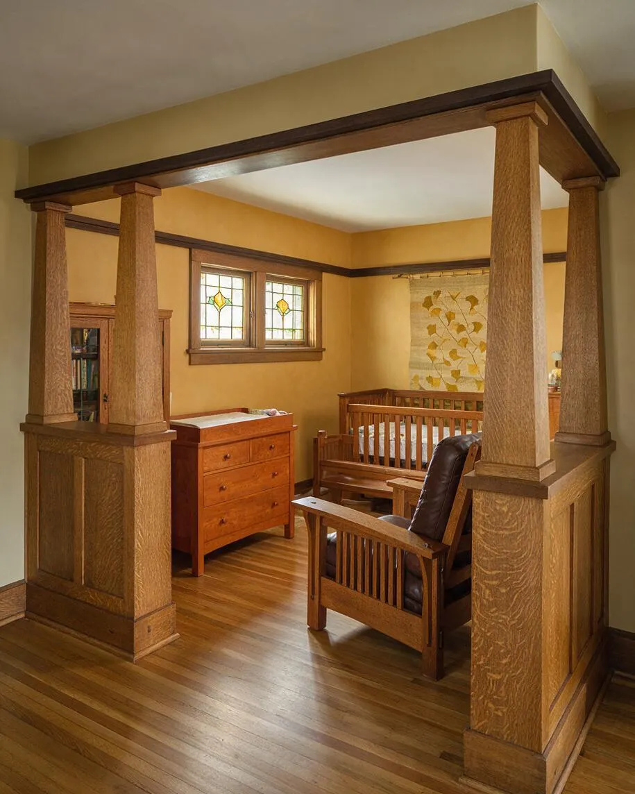 A Craftsman-style nursery with a large wood-framed opening supported by thick square columns, warm yellow walls, and polished hardwood floors. Inside the room are a wooden crib, a dresser with a changing top, a matching armchair, and small stained-glass windows that add a traditional handcrafted detail.