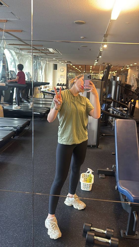 A person is taking a selfie in a gym, showcasing their workout attire and the gym environment.
