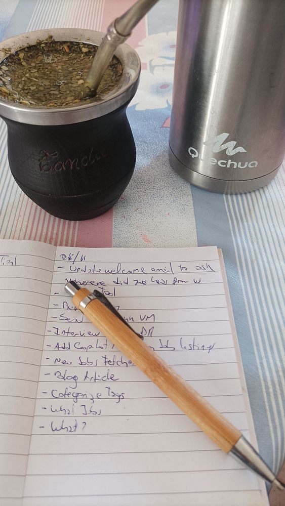 A cozy workspace featuring a traditional mate drink, a notebook filled with tasks, and a pen.