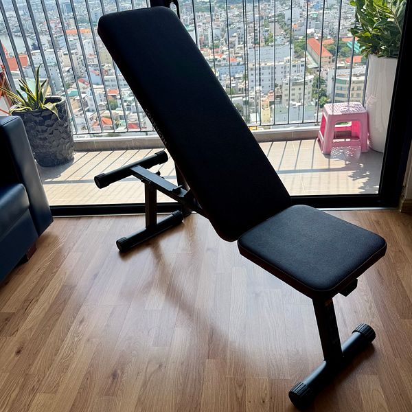 A new adjustable gym bench is positioned in a bright room with a city view.