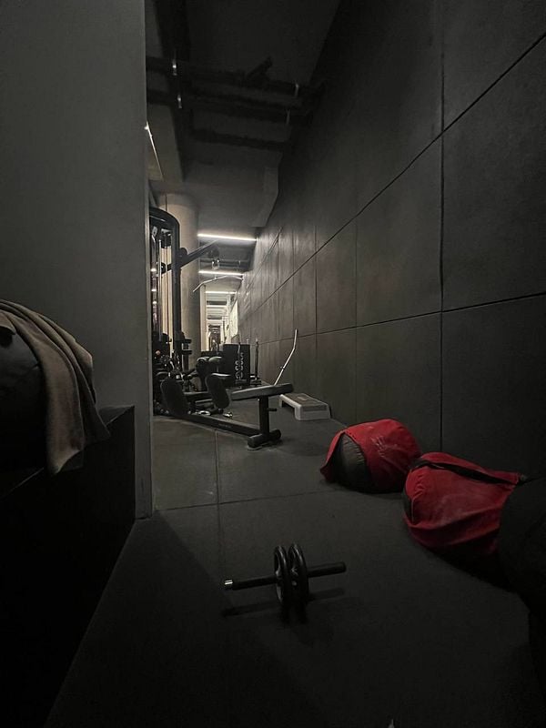 A dimly lit gym corridor featuring various workout equipment and accessories.