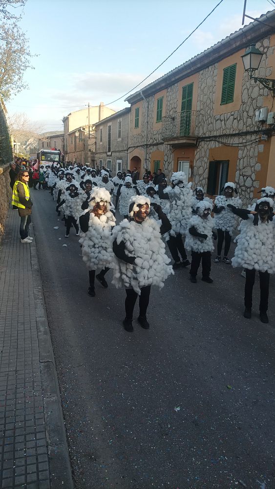 A lively street scene during a carnival parade featuring participants dressed as sheep.