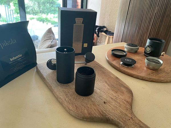 A stylish coffee setup featuring a portable grinder and espresso maker on a wooden surface.