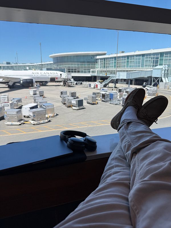 A traveler relaxes at the airport with a view of the tarmac and an Air Canada plane.