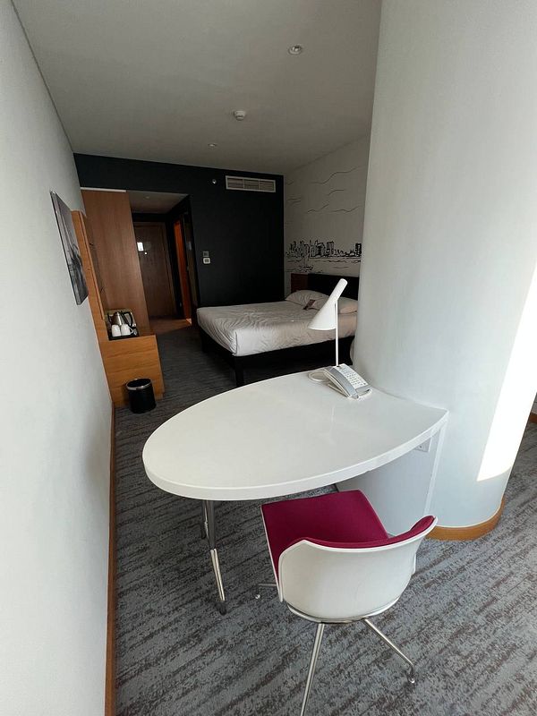 A modern hotel room featuring a bed, a workspace, and contemporary decor.