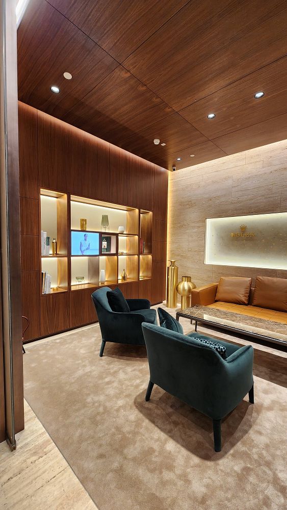 The image depicts a luxurious interior of a Rolex boutique featuring elegant seating and sophisticated decor.