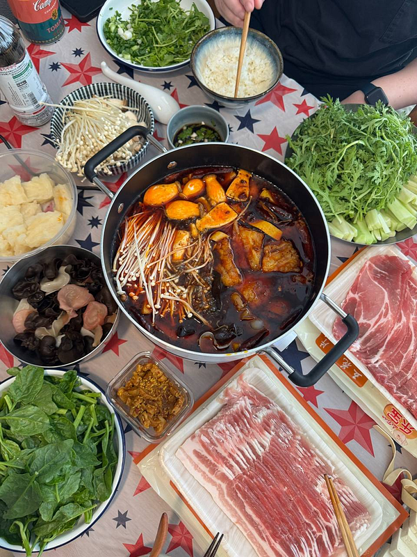 A table set with various dishes for a mala hotpot meal.