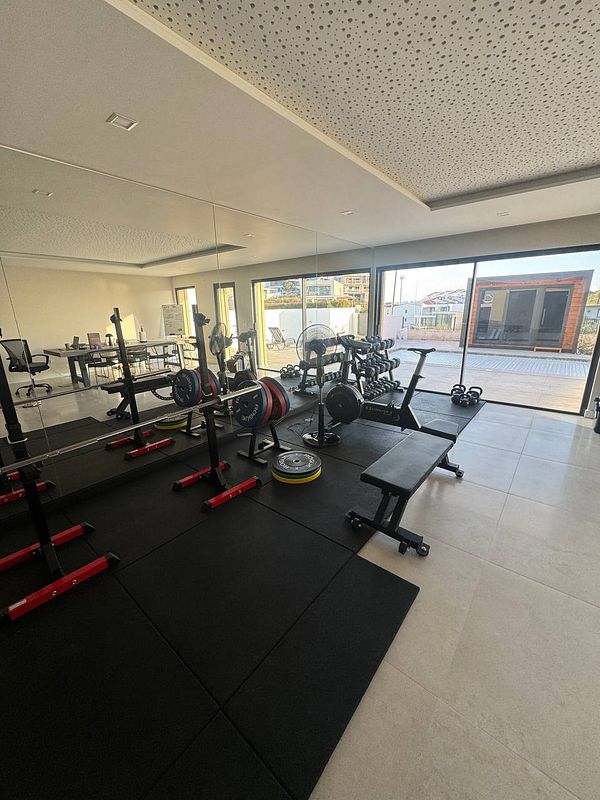 A modern home gym featuring various workout equipment and a spacious layout.