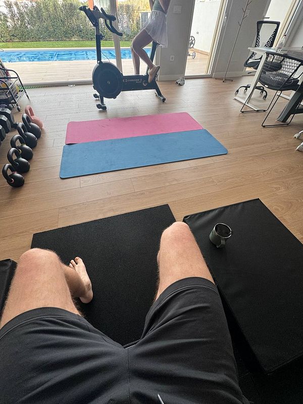 A home gym setup featuring exercise equipment and a person on a stationary bike.