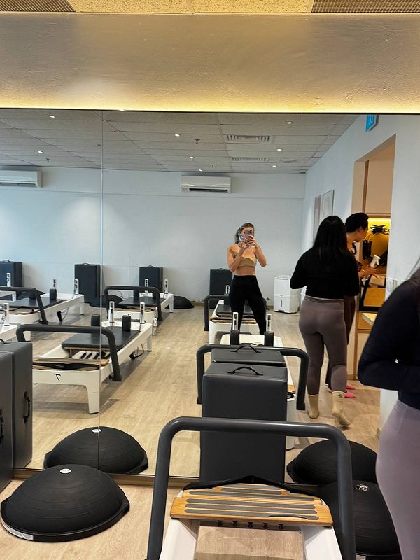 A pilates studio featuring workout equipment and individuals preparing for a session.