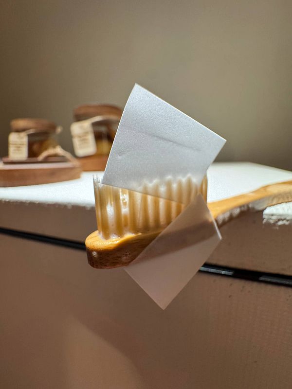 A toothbrush with eco-friendly toothpaste paper is displayed on a surface.