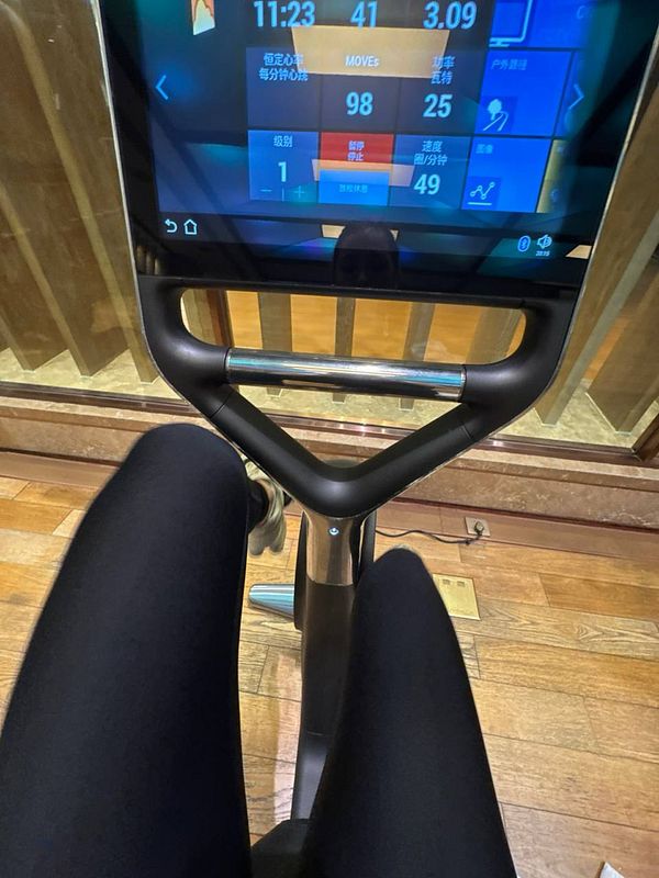 A person is using a stationary exercise bike in a gym setting.