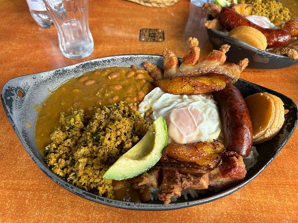 A vibrant Colombian dish served on a black plate, featuring a variety of ingredients.