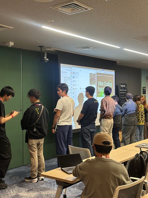 A group of participants is lined up in a tech event space during a hackathon in Tokyo.
