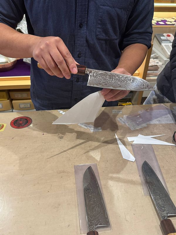 A person is demonstrating a Japanese knife in a store setting.