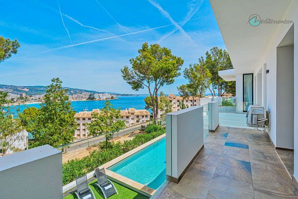 A stunning balcony view overlooking a coastal area with a swimming pool and lush greenery.