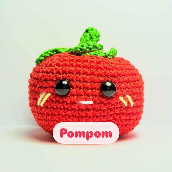 A cute, crocheted tomato plush toy named 'Pompom' is displayed against a plain background.