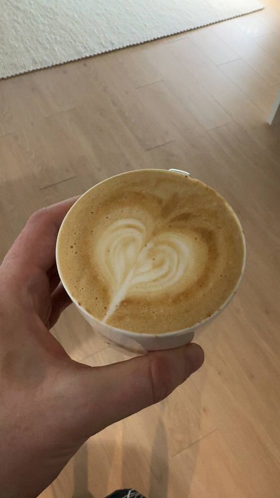 A cozy coworking space with two laptops, coffee, a notebook, and phone on a wooden table under warm lighting.