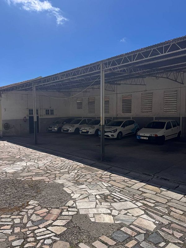 A parking area with several cars under a covered structure.