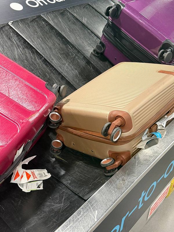 Damaged suitcases with broken wheels on Lisbon Airport baggage carousel causing inconvenience.