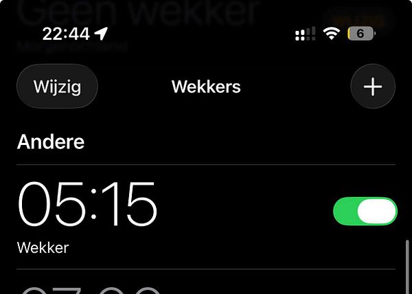 A nighttime cityscape of Amsterdam with buildings, a canal, and their lights reflected in the water under a dark sky.