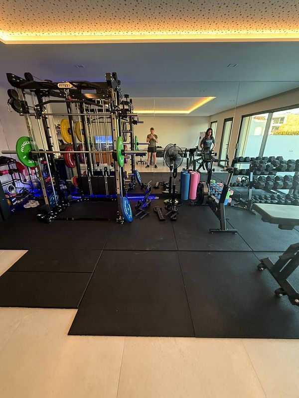 A well-equipped home gym featuring various workout equipment and two individuals.