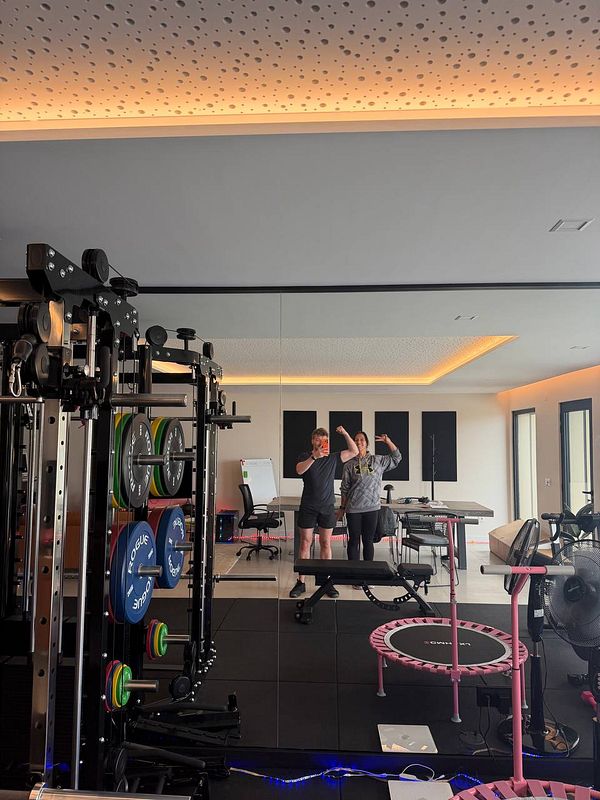 Photo of gym interior featuring exercise equipment such as bikes and benches with a motivational poster on the wall.