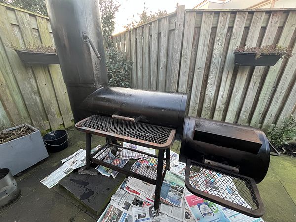 A second-hand smoker BBQ is set up for restoration in an outdoor space.