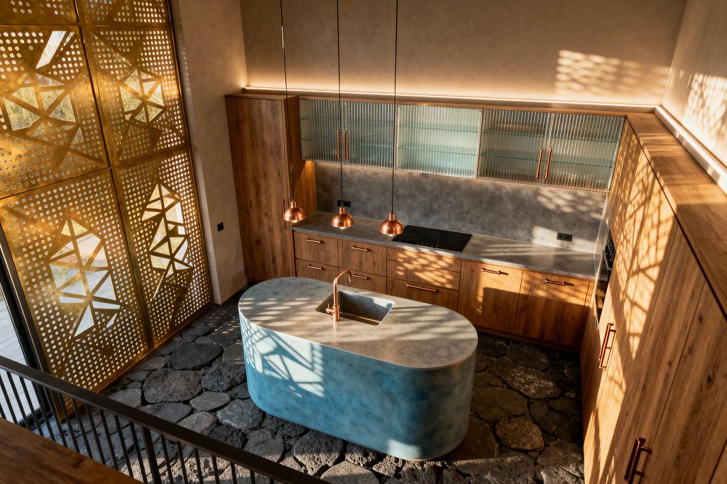 A contemporary kitchen features an oval blue concrete island with an integrated sink and copper faucet set on dark stone flagstone flooring. Warm oak cabinets with copper pulls line one wall beneath reeded-glass uppers and a gray concrete worktop; three copper dome pendants and concealed LED strips illuminate surfaces as sunlight filters through a perforated gold metal screen, casting geometric shadows across the space.