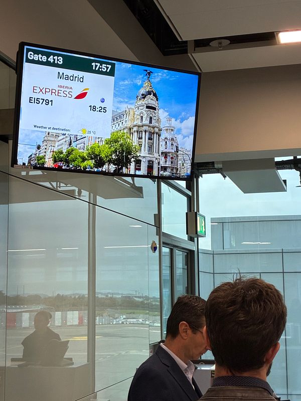 A flight information display board at an airport shows details for a flight to Madrid.