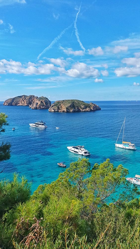A picturesque coastal scene featuring boats in a vibrant blue sea with islands in the background.