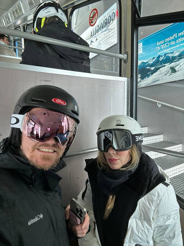 A couple is preparing to ski inside a gondola lift.