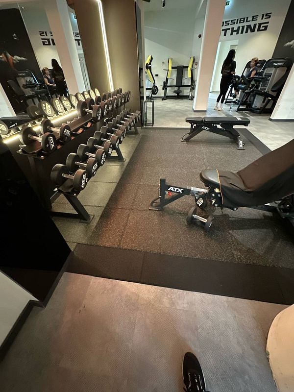 A well-equipped gym area featuring dumbbells, a bench, and various exercise machines.